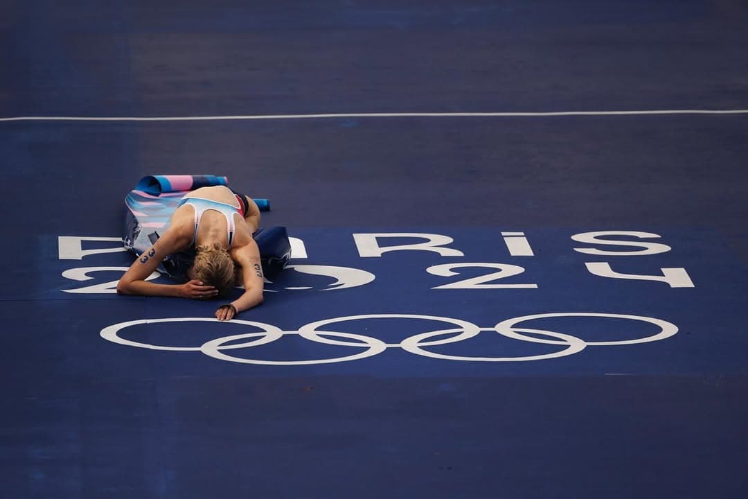 Cassandre Beaugrand effondrée sur la ligne d'arrivée de Paris 2024, les anneaux olympiques sous elle.